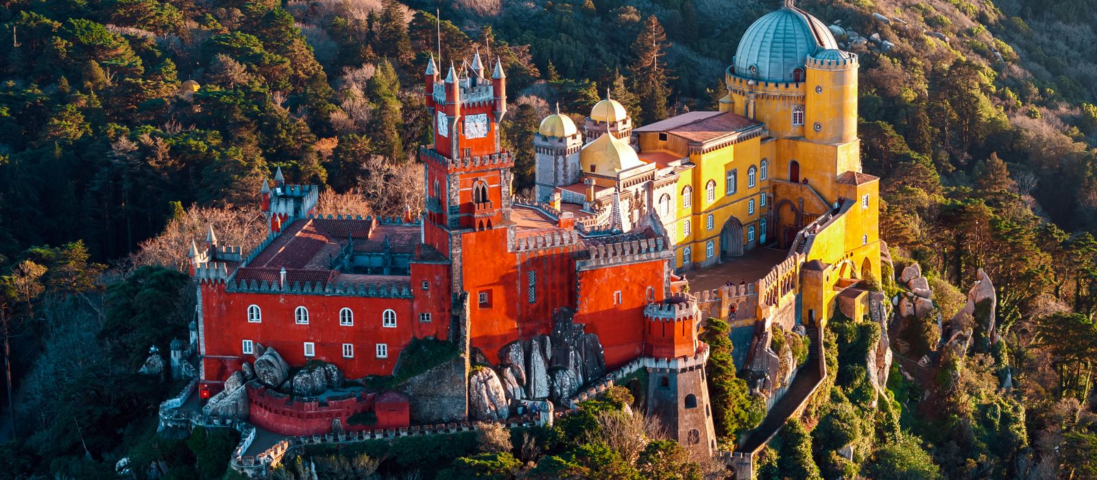 Breathtaking aerial shot of the colorful Pena Palace nestled in the lush hills of Sintra, Portugal.