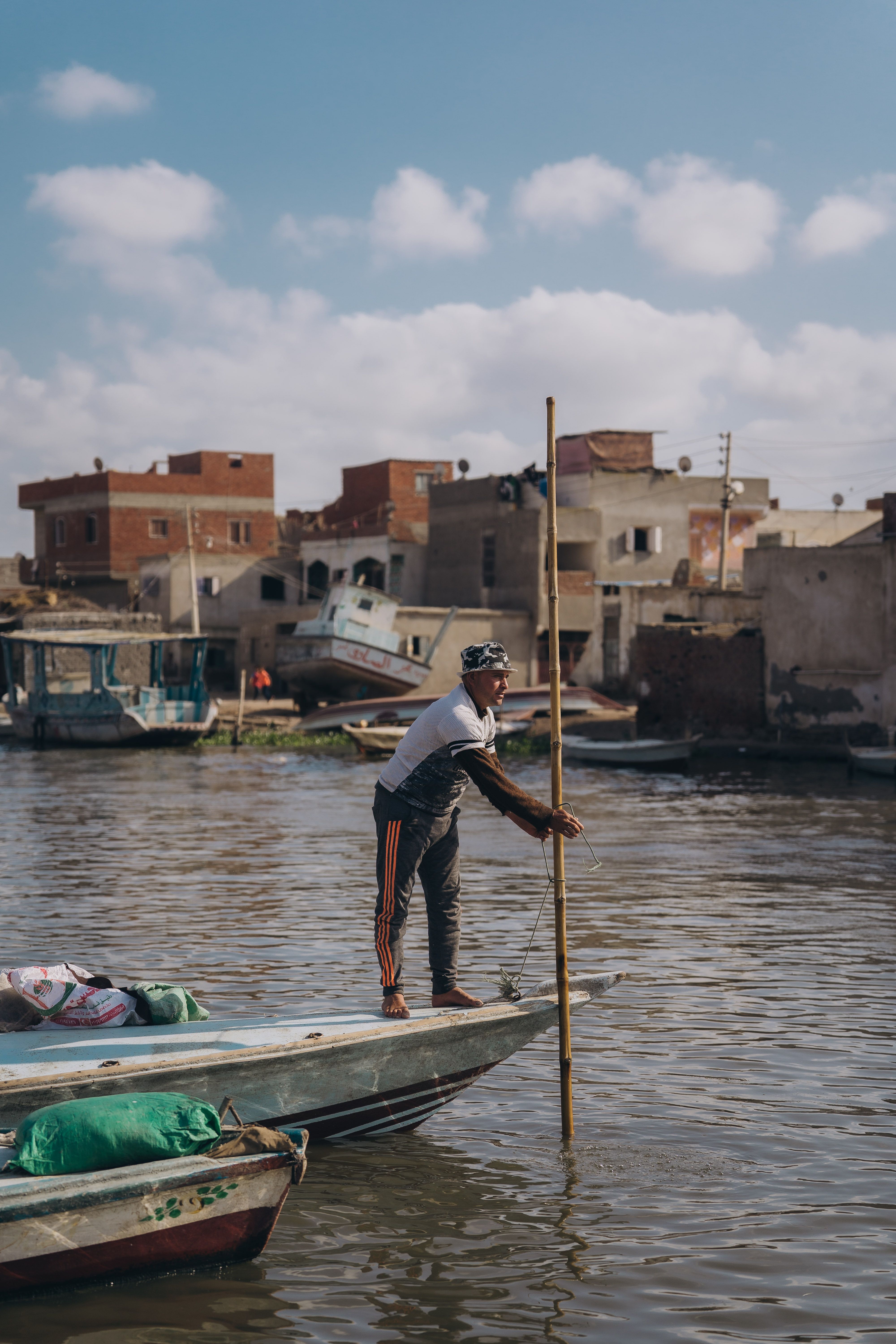 A local fisherman navigates a boat along a canal in Kafr El-Shaikh, Egypt. Clear skies above.