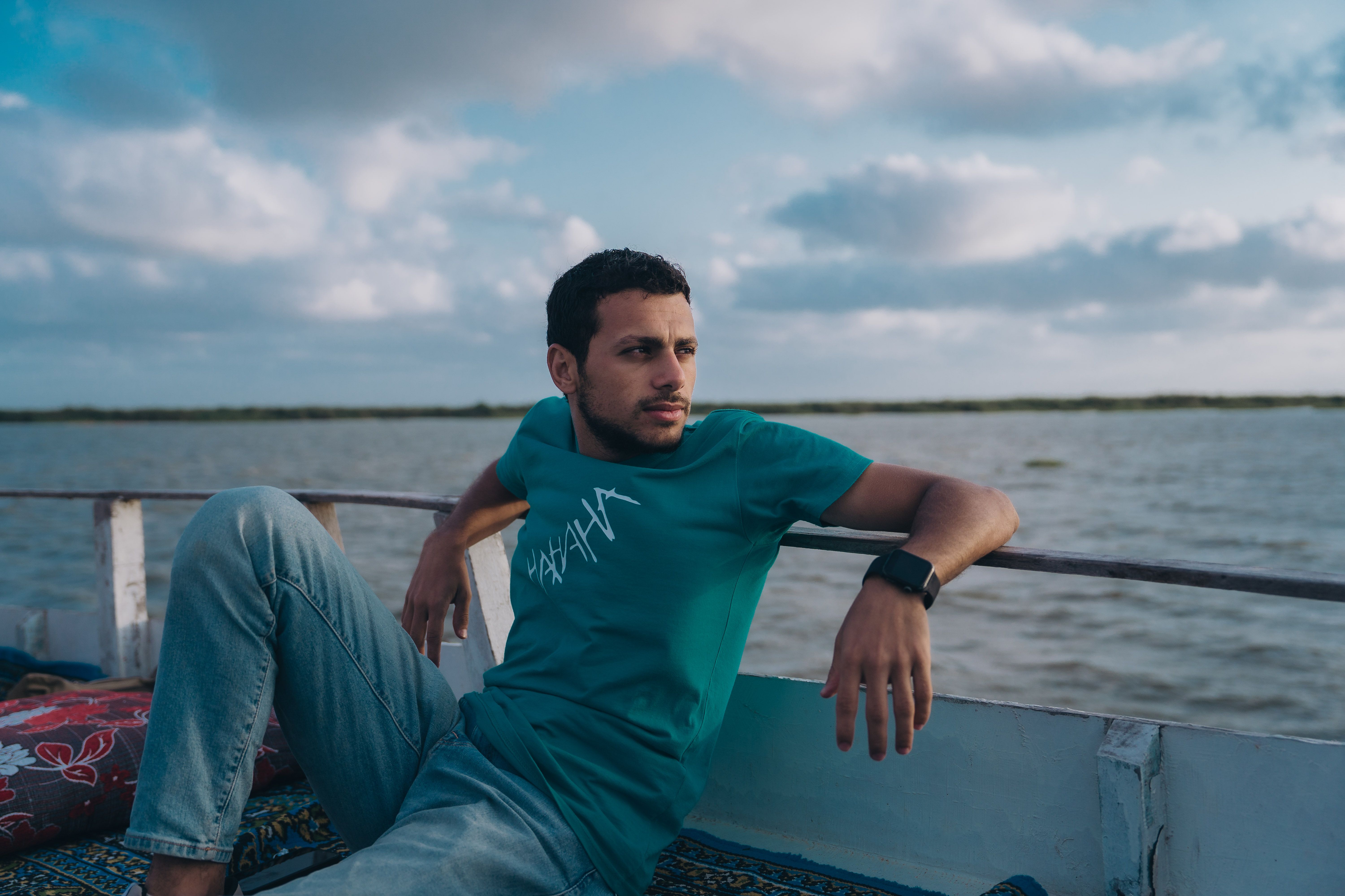 Man relaxing on a boat in Kafr El-Shaikh, Egypt, under a beautiful sky.