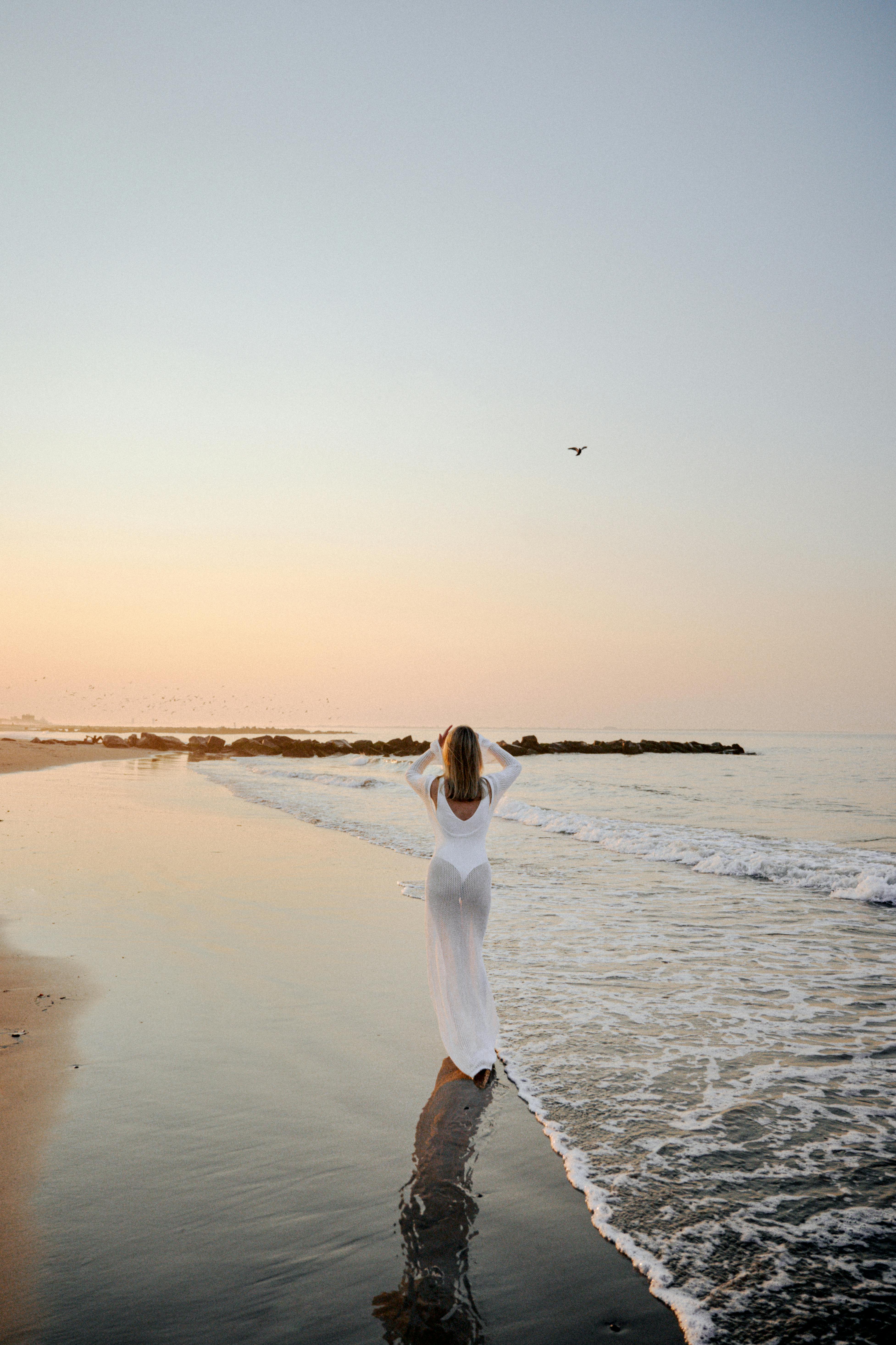 a woman in a white dress standing on the beach