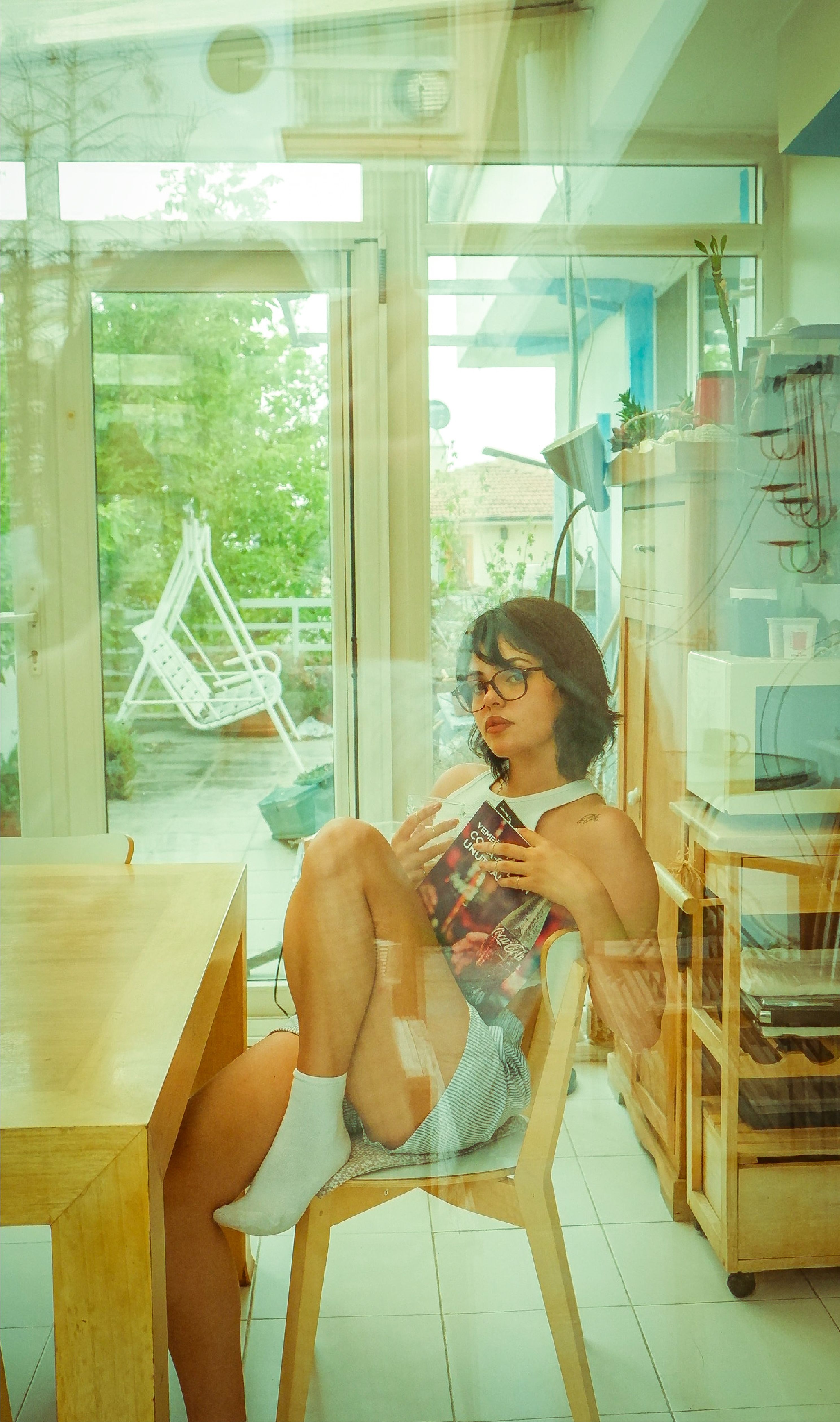 Young woman relaxing in modern indoor space with glass doors, embracing leisure and tranquility.