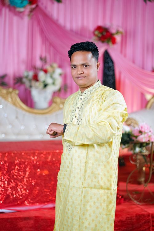Free A man in traditional attire poses at a vibrant, floral-themed celebration. Stock Photo