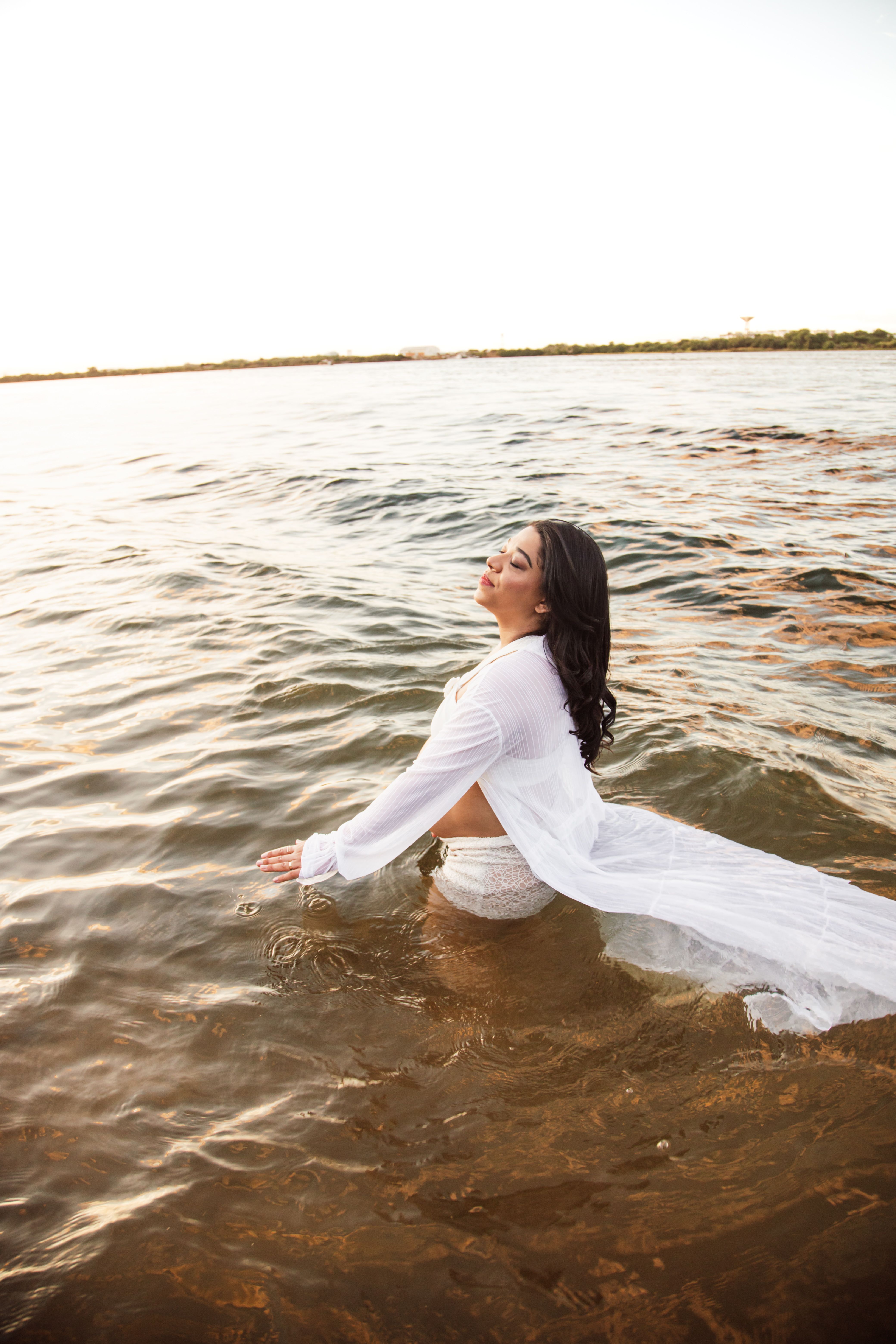 A woman in a white dress is standing in the water · Free Stock Photo