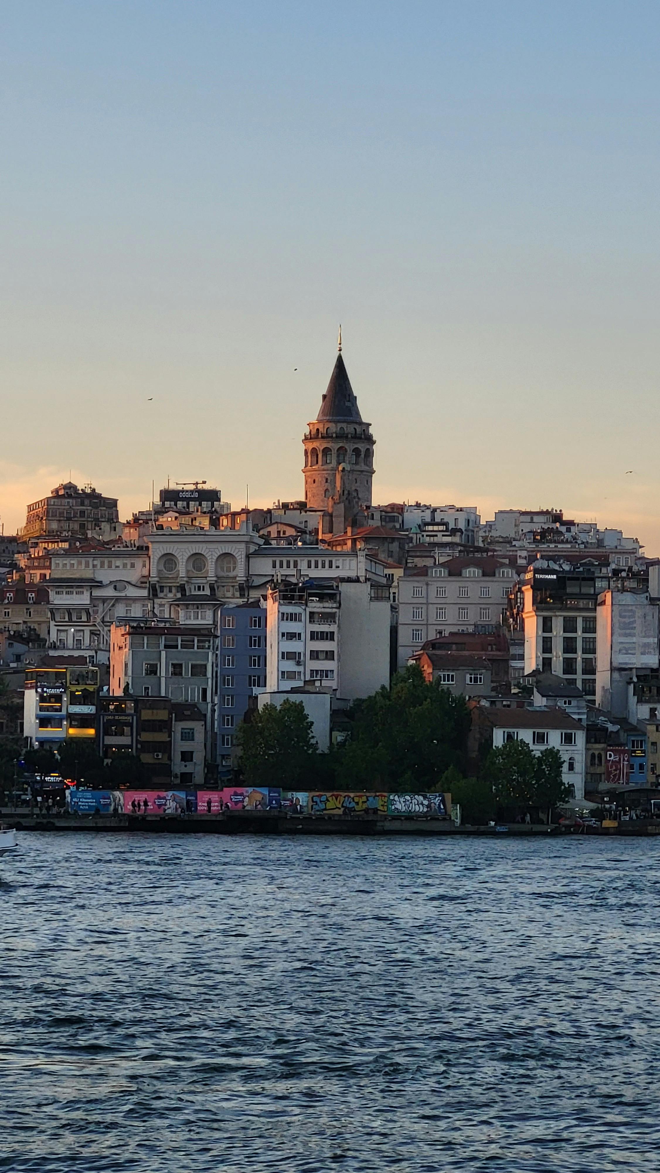 View of Galata Tower in Istanbul during sunset reflecting on the river.