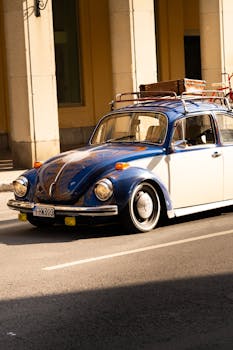 Classic vintage blue and white car with luggage racks cruising an urban street.