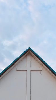 A cross on a church roof in Accra, Ghana, beneath a serene blue sky.