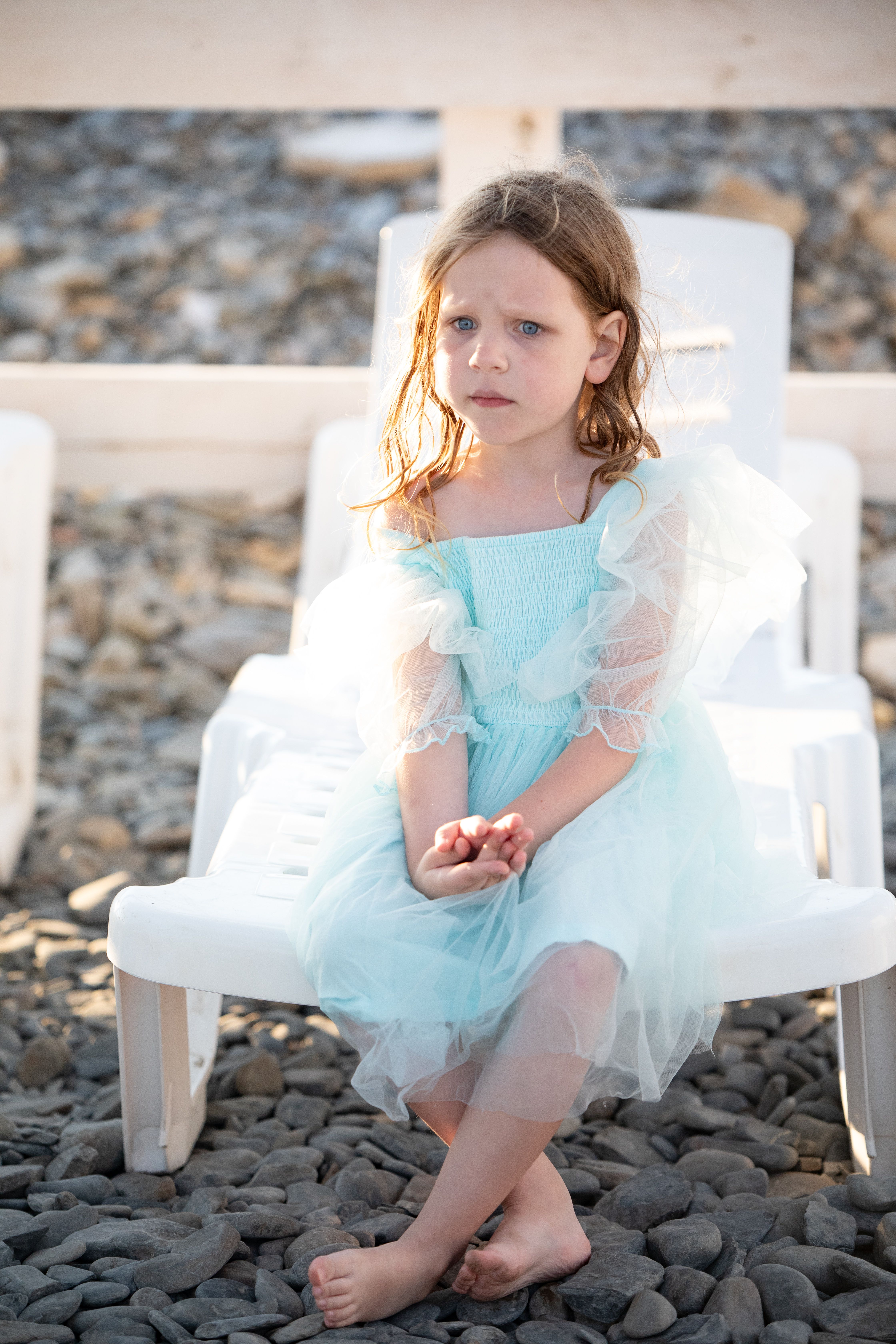 A little girl in a blue dress sitting on a chair · Free Stock Photo