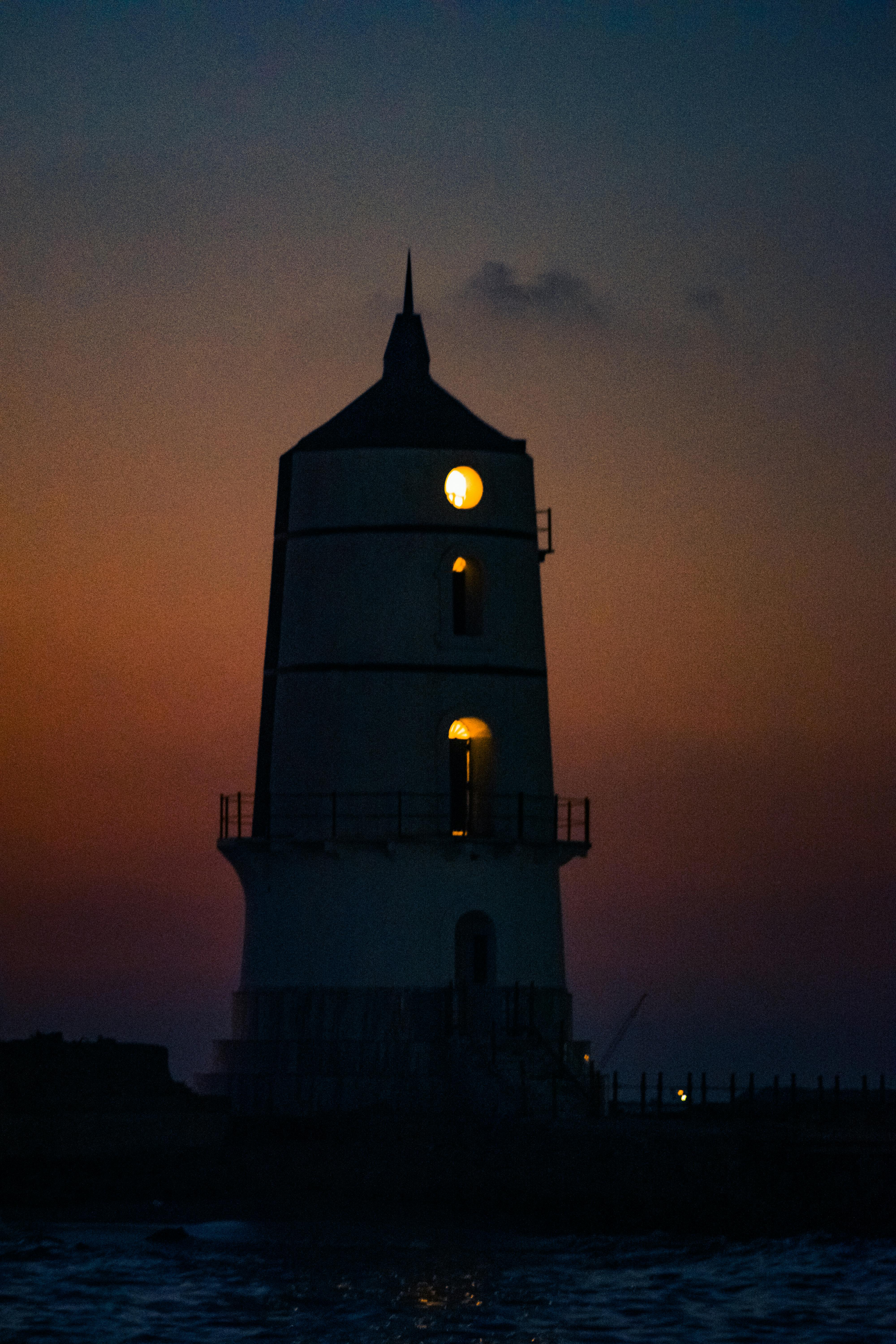 Silhouette of a lighthouse against a vibrant sunset sky in Alexandria, Egypt.