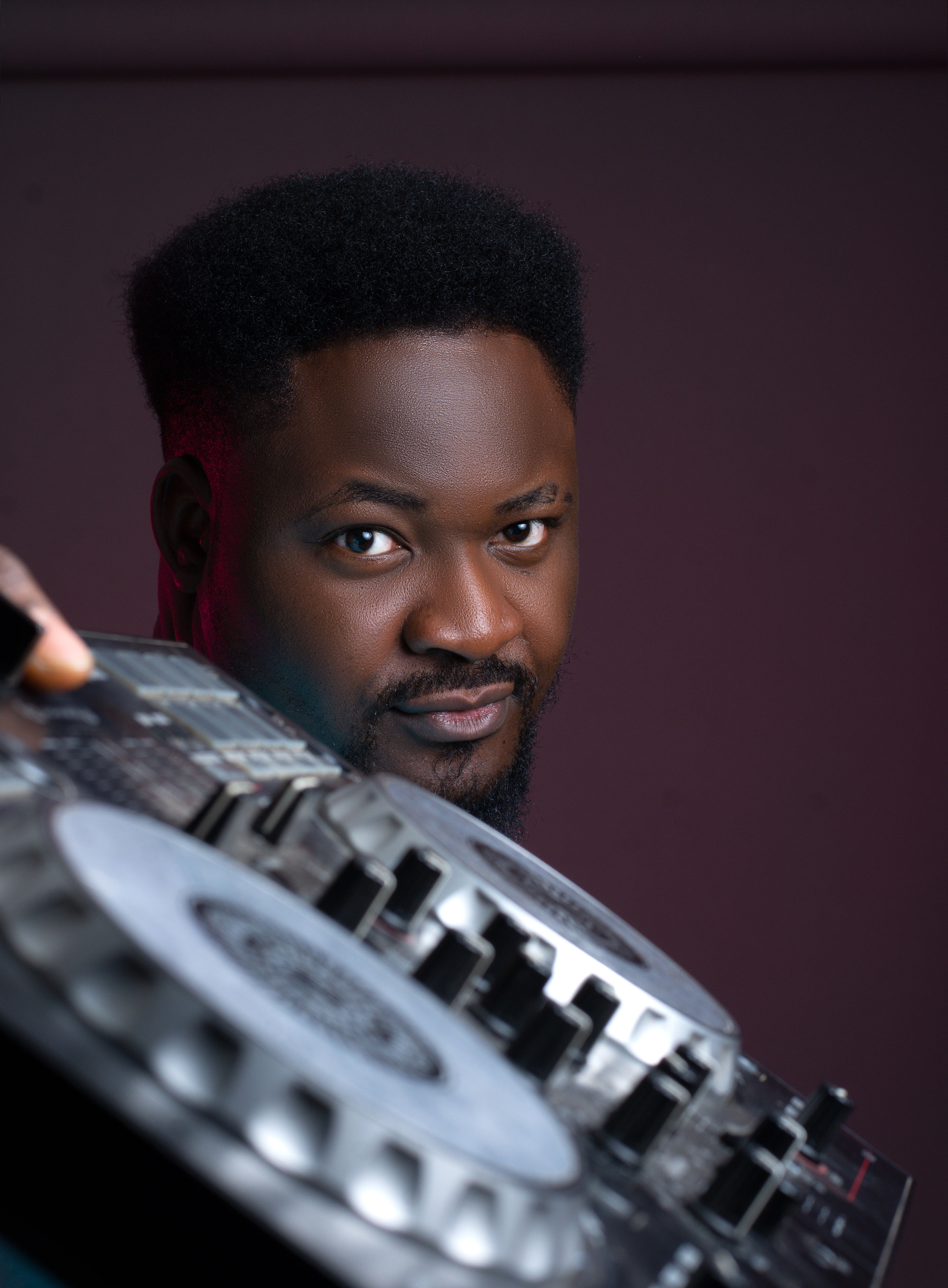 Close-up portrait of a DJ holding a turntable in a studio setting, showcasing focus and creativity.