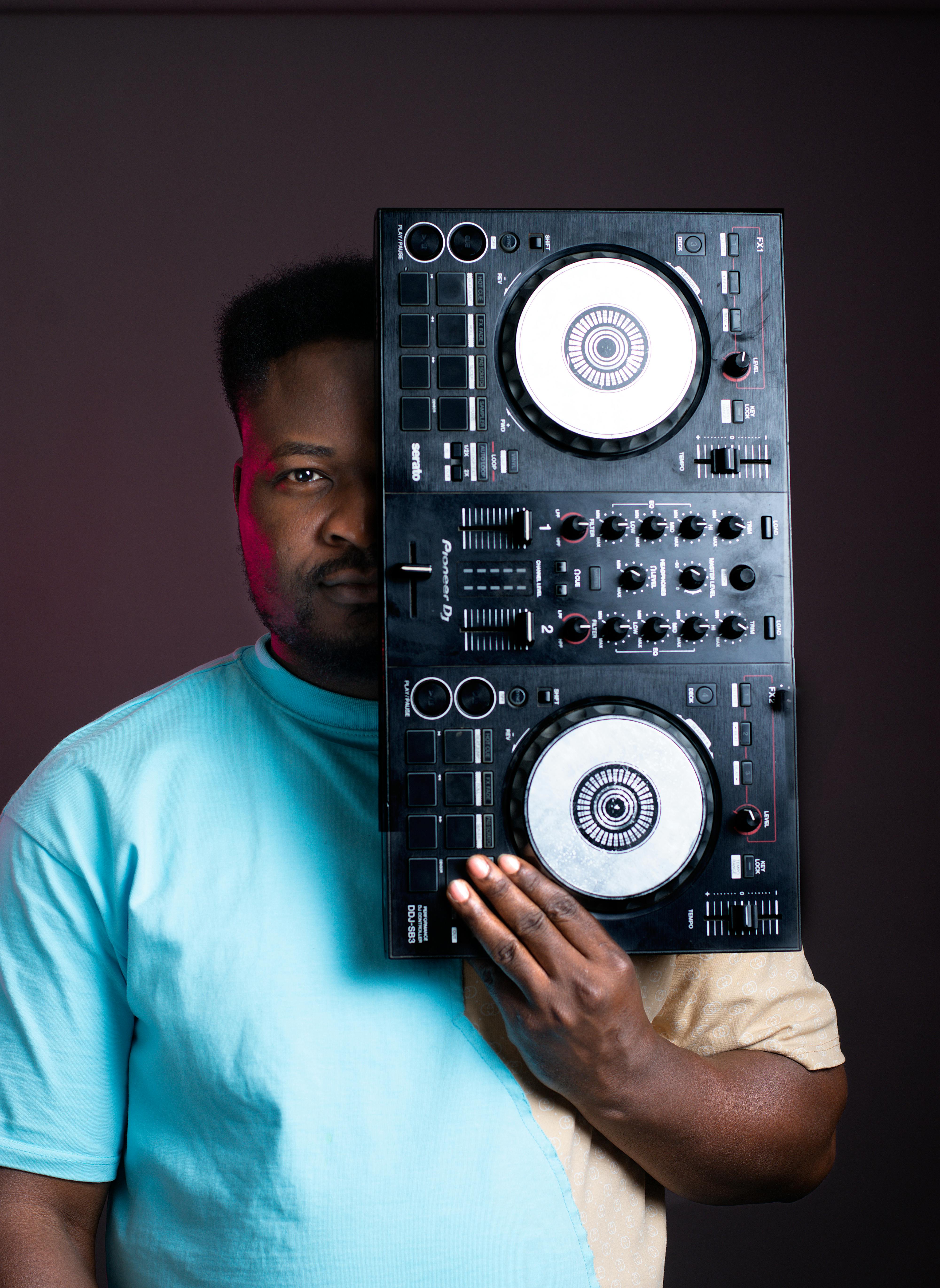 Young DJ holding a DJ controller, blending modern music technology and style.