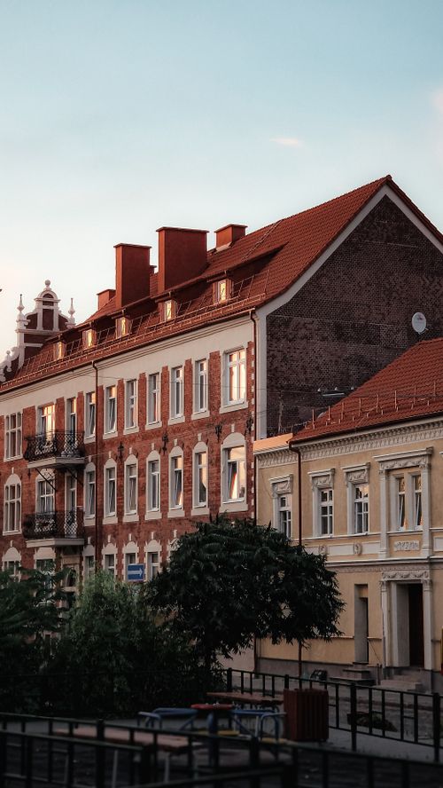 Free Red brick and stucco buildings in a European street setting, showcasing charming architectural details at dusk. Stock Photo