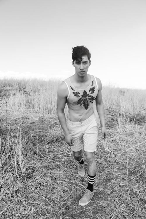 Man in Tank Top Walking on Grass Field