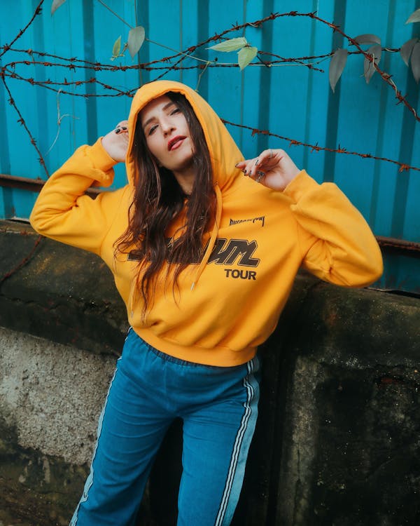 Photo of Woman in Yellow Hoodie and Blue Pants Posing