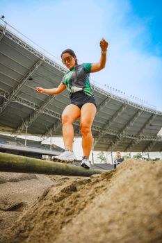 Dynamic shot of a woman balancing on a beam in an open stadium, showcasing athletic skill.
