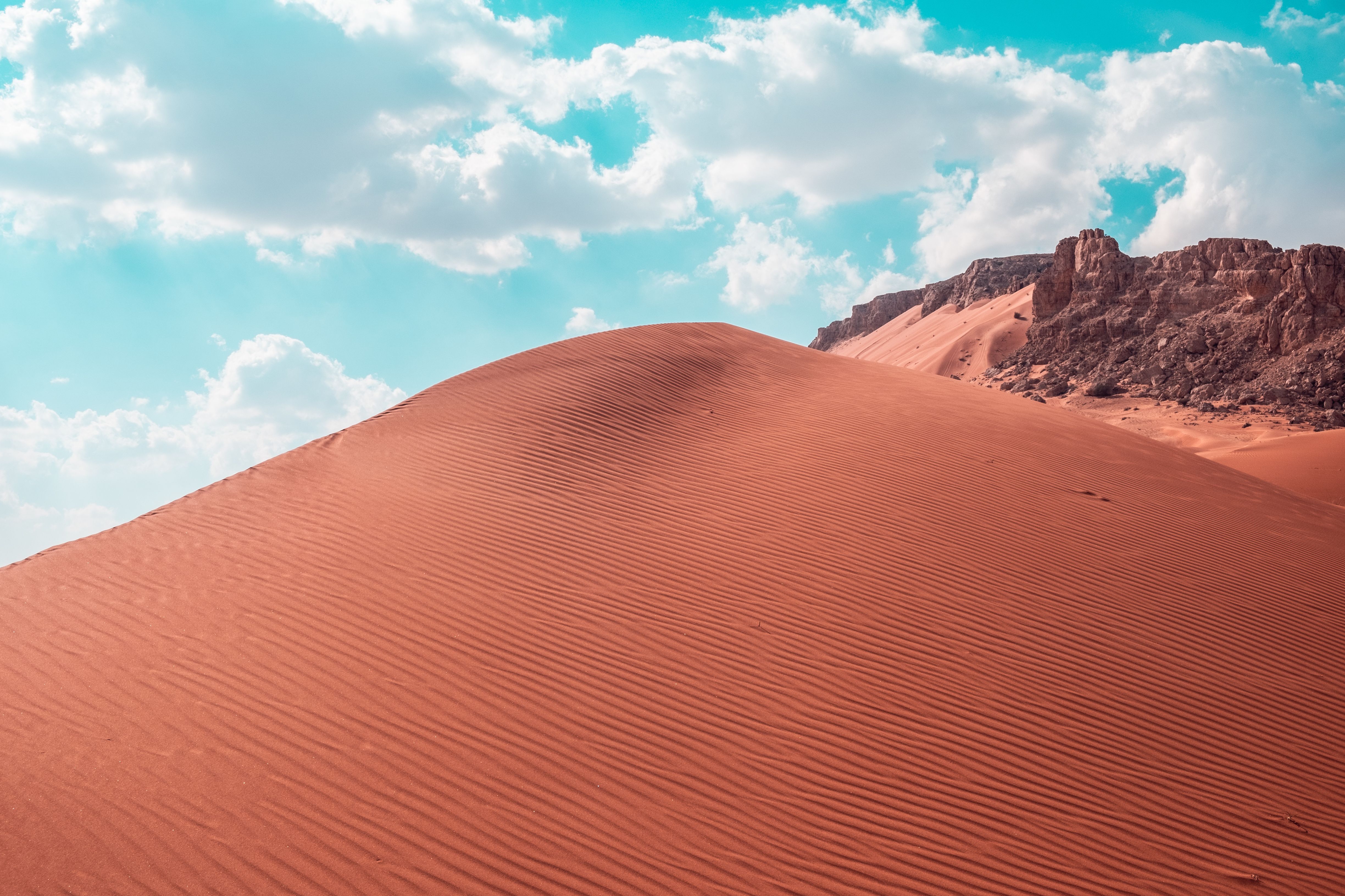 A red sand dune in the desert with clouds · Free Stock Photo