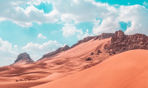 Free Vast desert scene featuring dramatic sand dunes and rocky mountains. Stock Photo