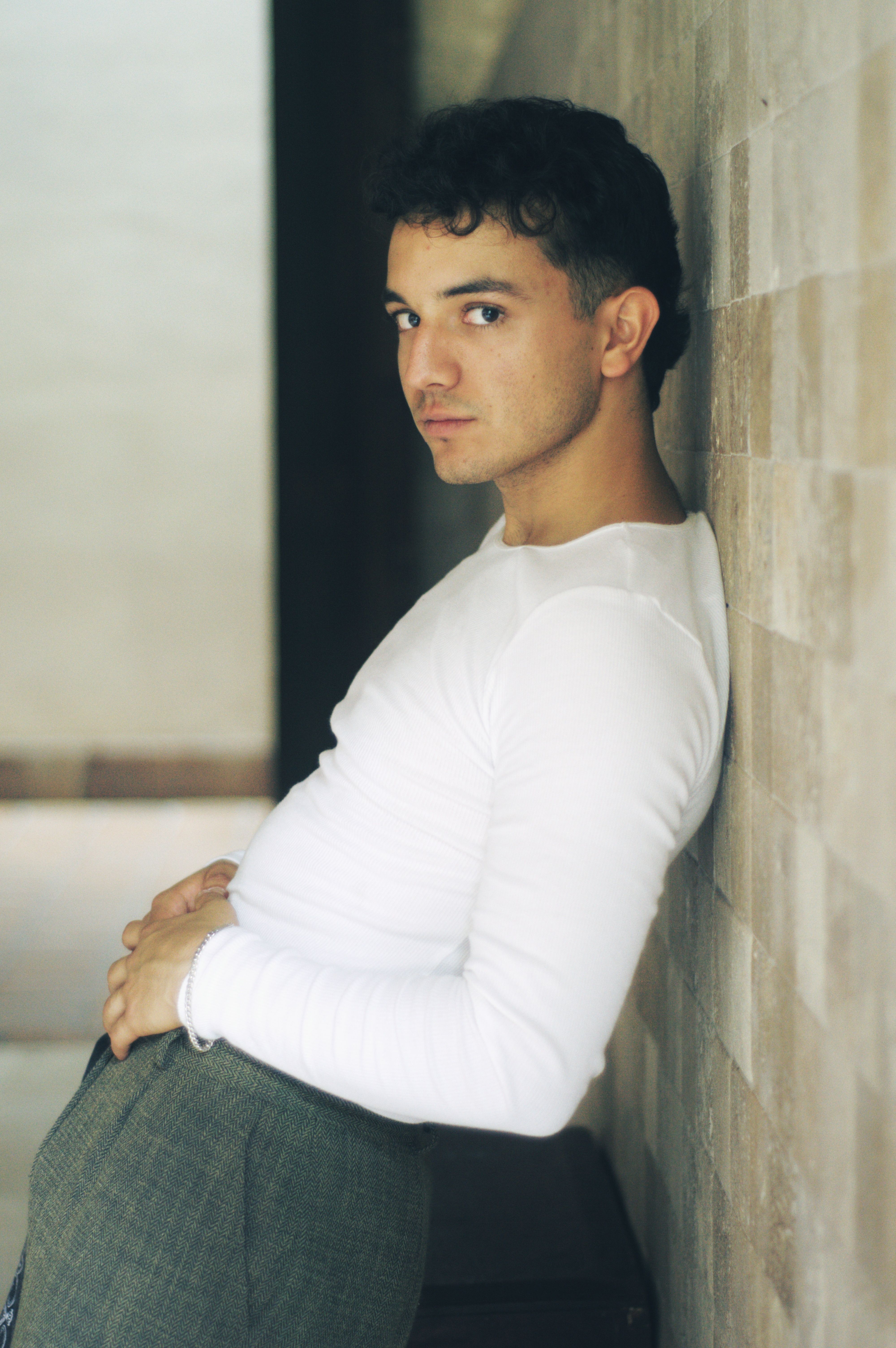 Portrait of a thoughtful young man in casual fashion indoors, exuding contemporary coolness.