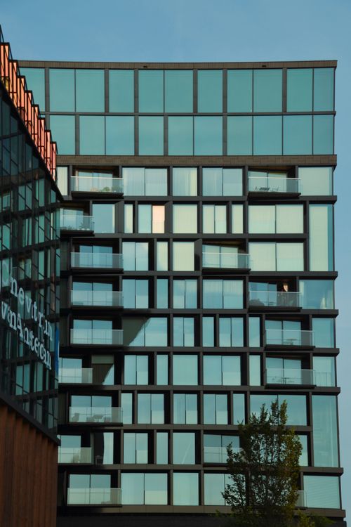 Free A contemporary skyscraper with a unique reflective glass facade in a bustling urban area, showcasing modern architecture. Stock Photo