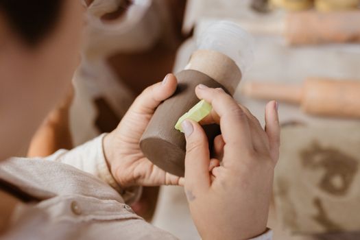 A person skillfully crafting pottery in an indoor setting, showcasing detailed handwork and craftsmanship.