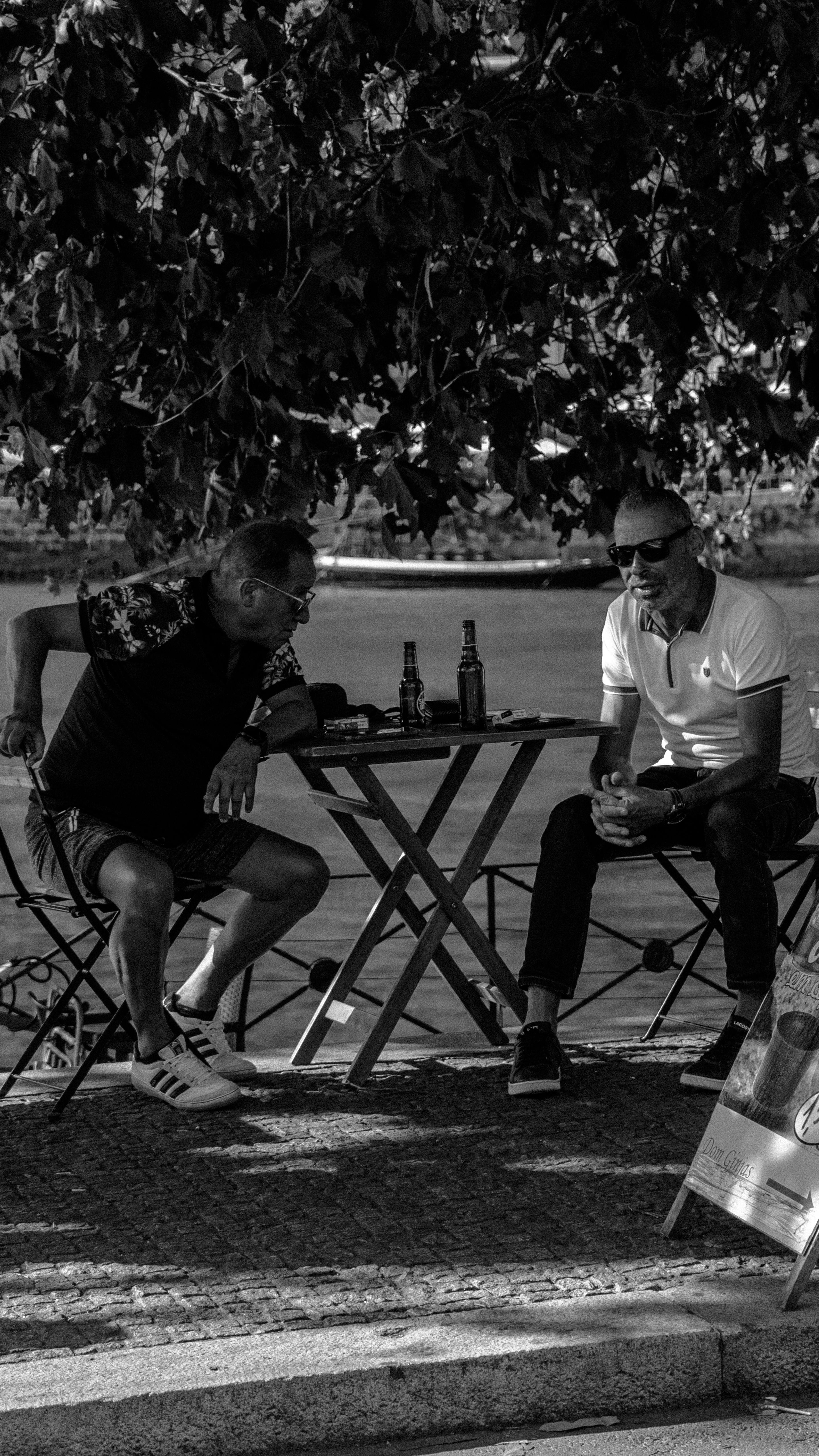 Two men enjoying a casual conversation outdoors in Porto, captured in artistic black and white.