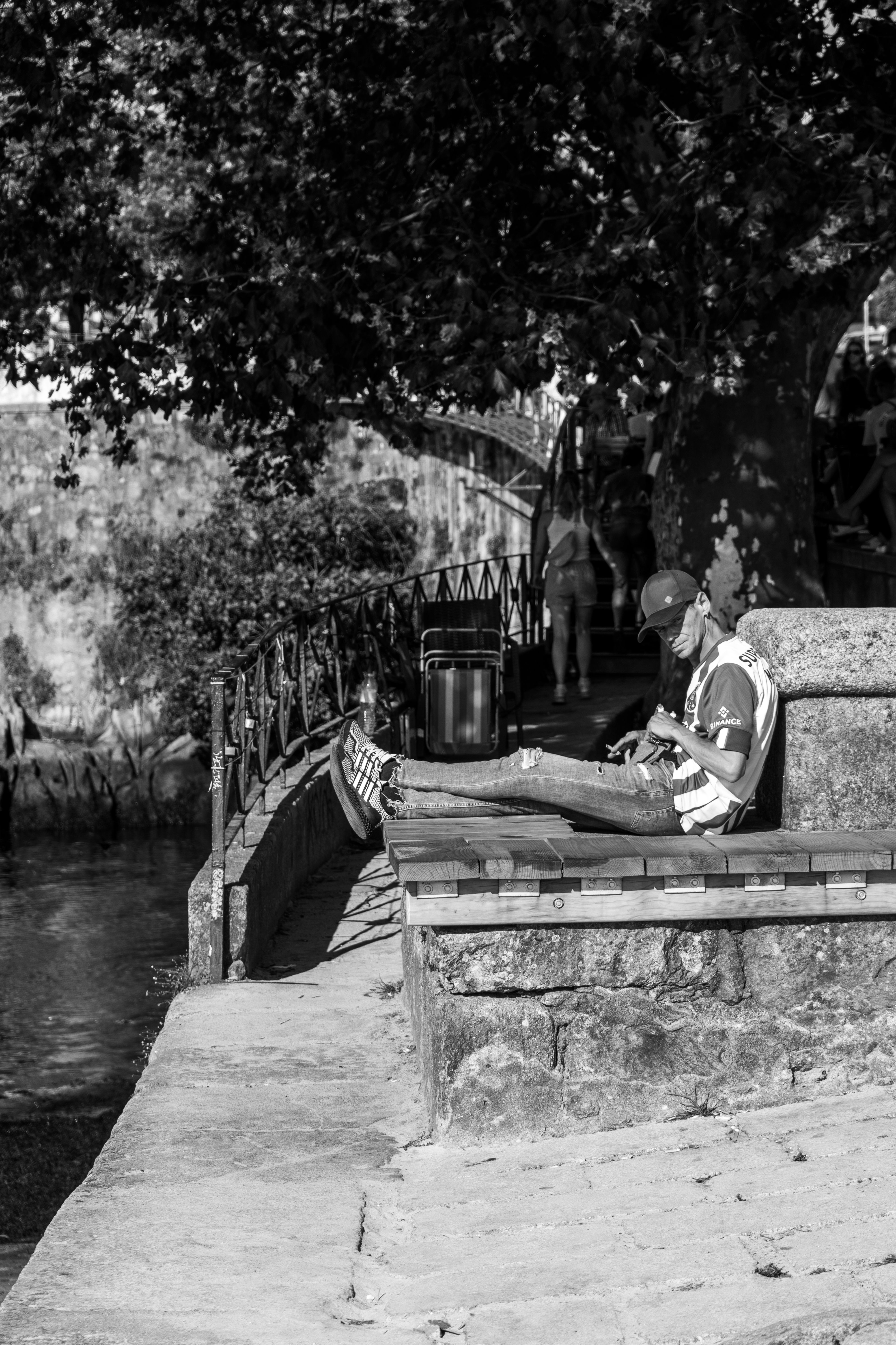 A young man sitting on a bench by the Douro River in Porto, enjoying the tranquil atmosphere of the city.