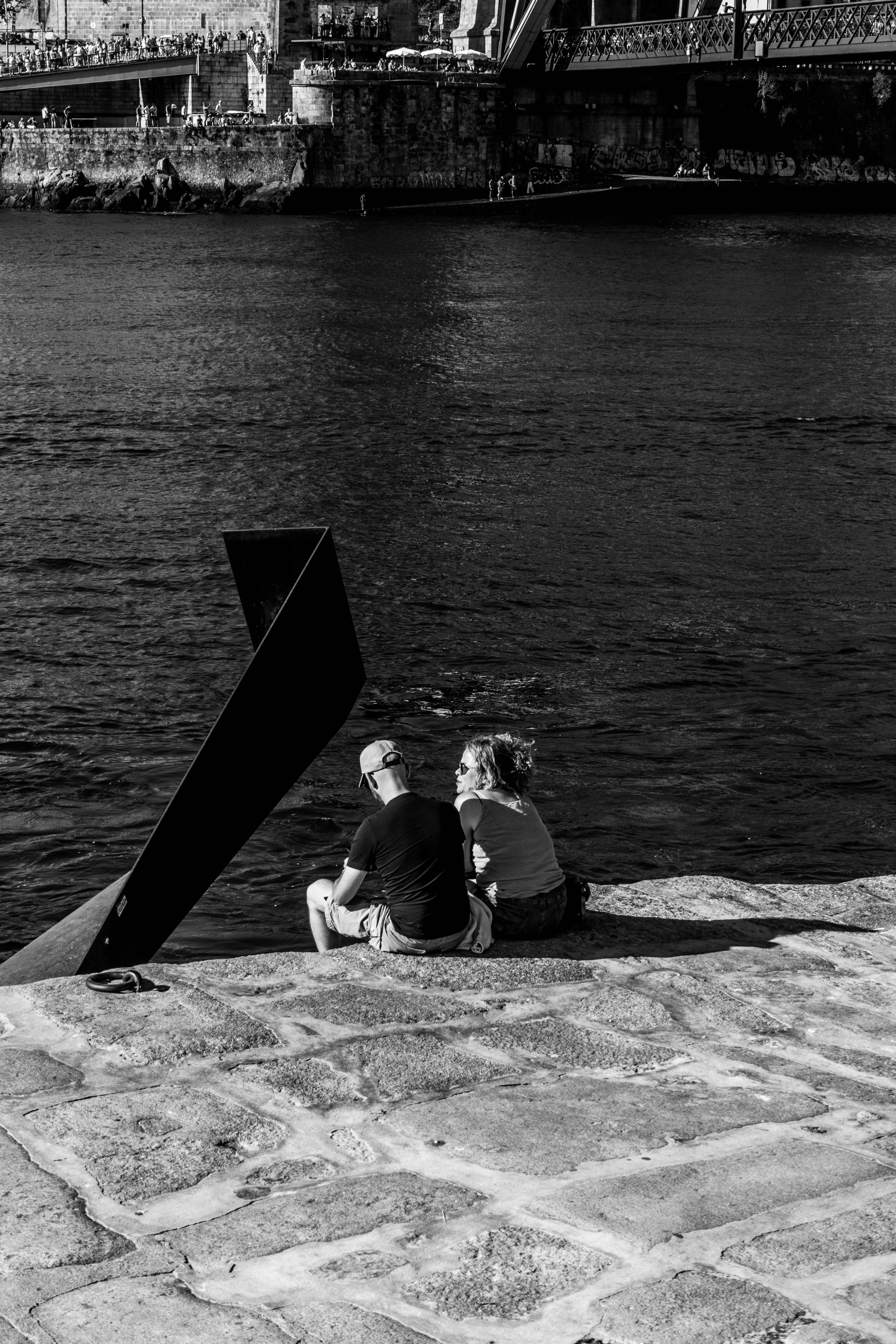 Two people sitting on the edge of a river · Free Stock Photo