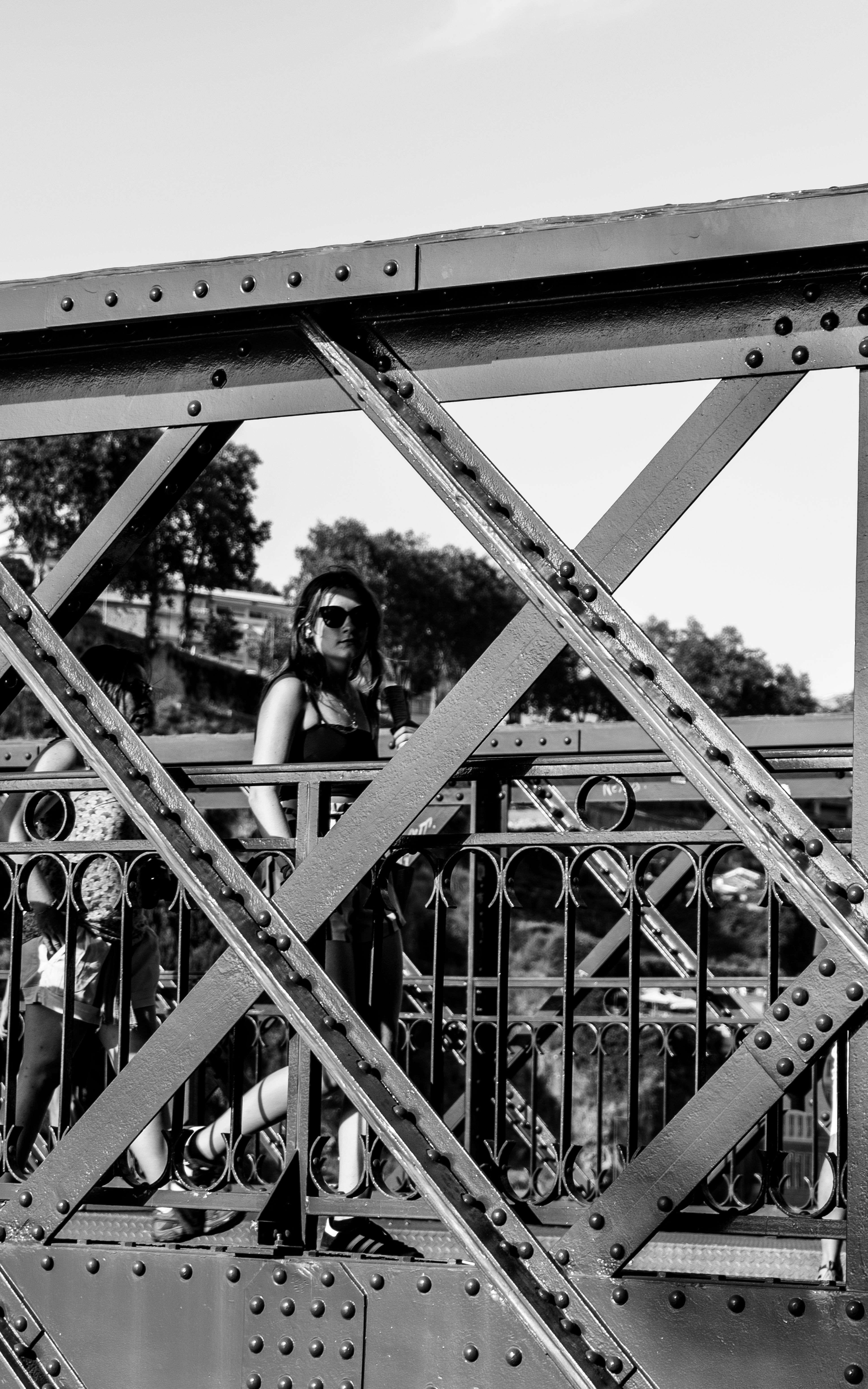 Black and white photo of a woman on a metal bridge in Porto, Portugal.