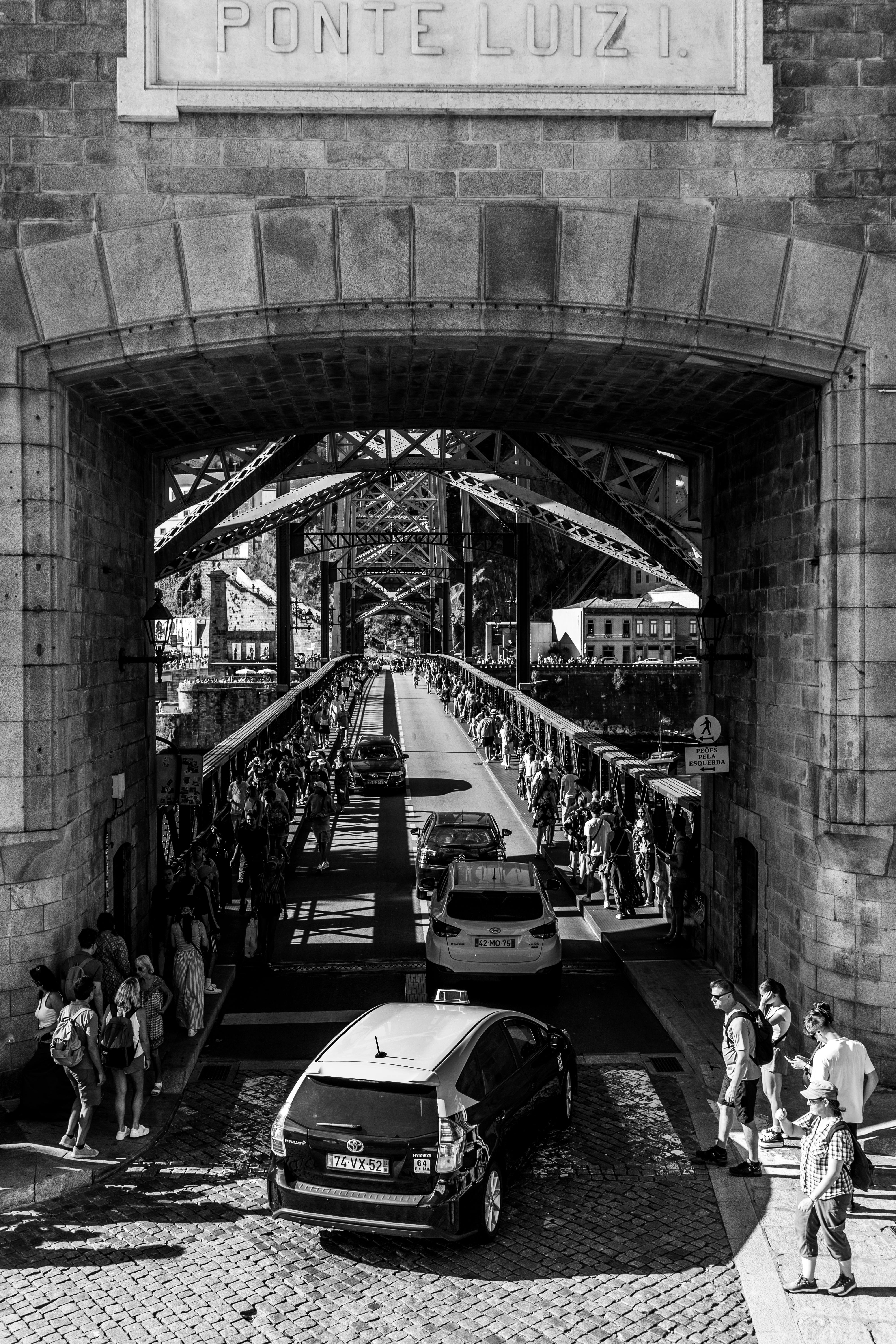 a black and white photo of cars driving under a bridge