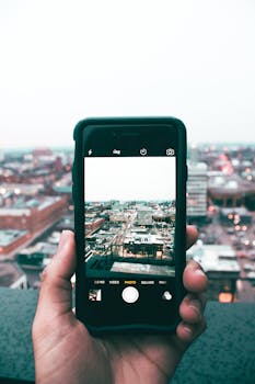 A person captures a rooftop cityscape in Kitchener, Canada, using a smartphone camera.
