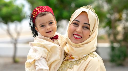 Free Mother and child smiling outdoors in traditional Tunisian clothing, capturing a joyful family moment. Stock Photo