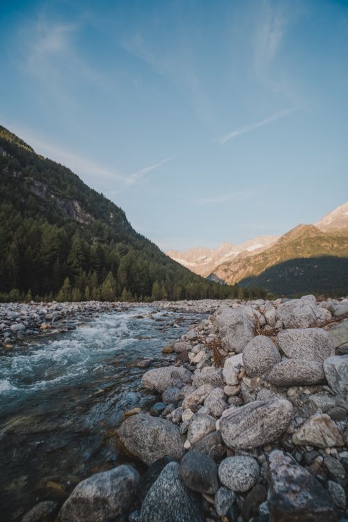 Free Idyllic mountain river flowing through rocky landscape under a clear sky at sunset. Stock Photo