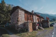 A rustic stone cabin with wooden accents, set against a tranquil mountain backdrop with vibrant nature.