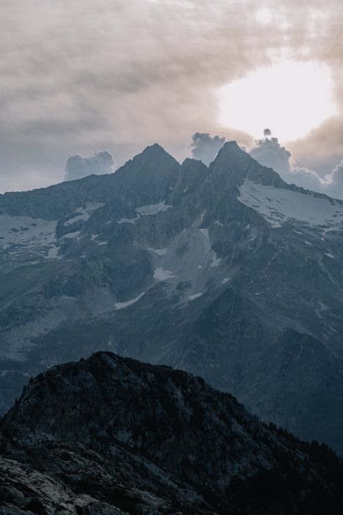 Free Dramatic mountain scene with snow and clouds at sunrise, perfect for adventure and travel themes. Stock Photo