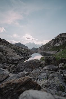 A peaceful mountain scene featuring a tranquil lake and rocky terrain under a clear sky.