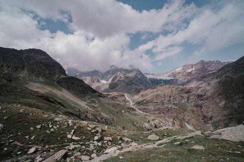 Free A beautiful mountain valley view with rocky peaks, clouds, and lush greenery in summer. Stock Photo
