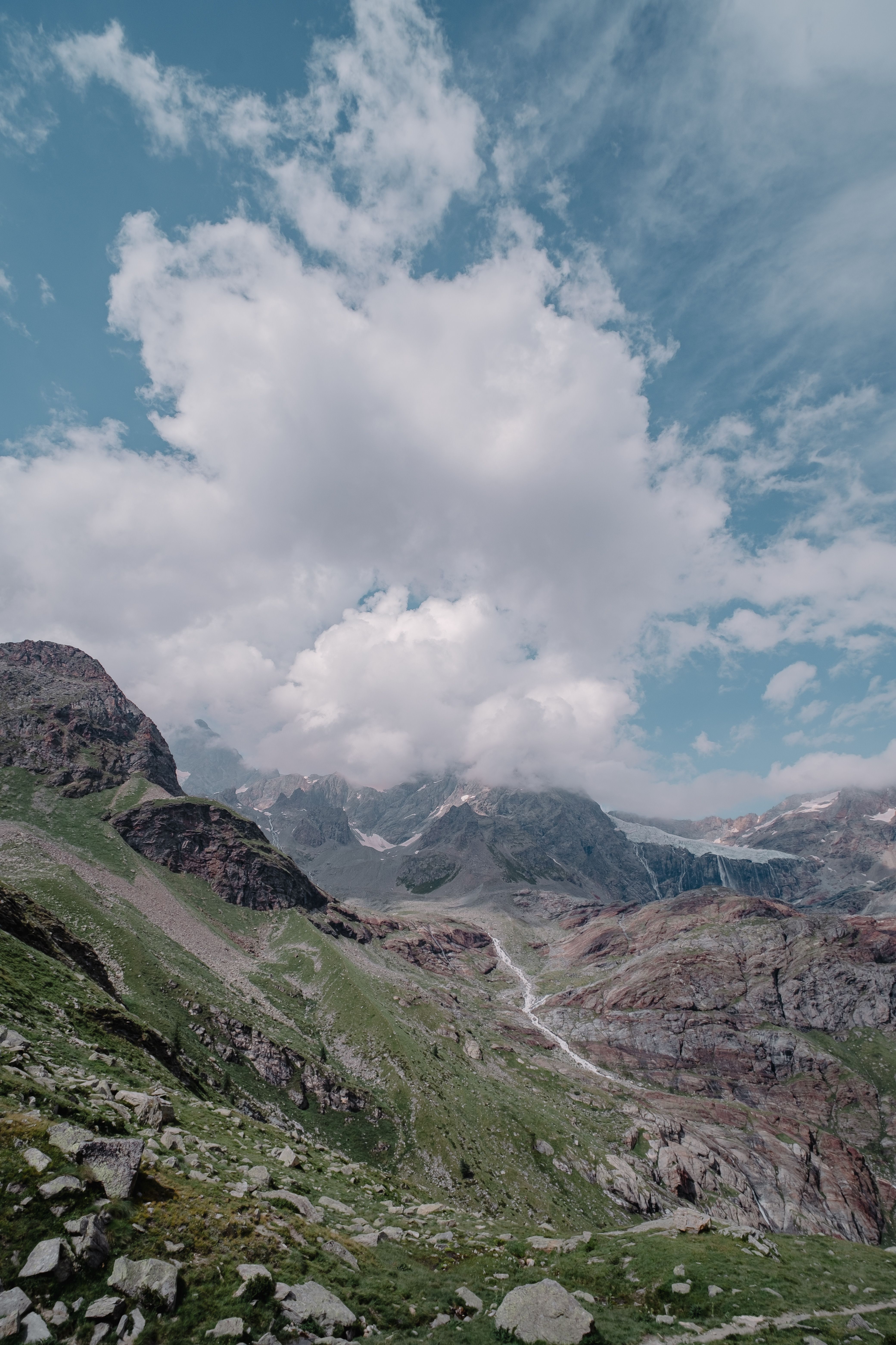 A mountain range with clouds and a valley · Free Stock Photo