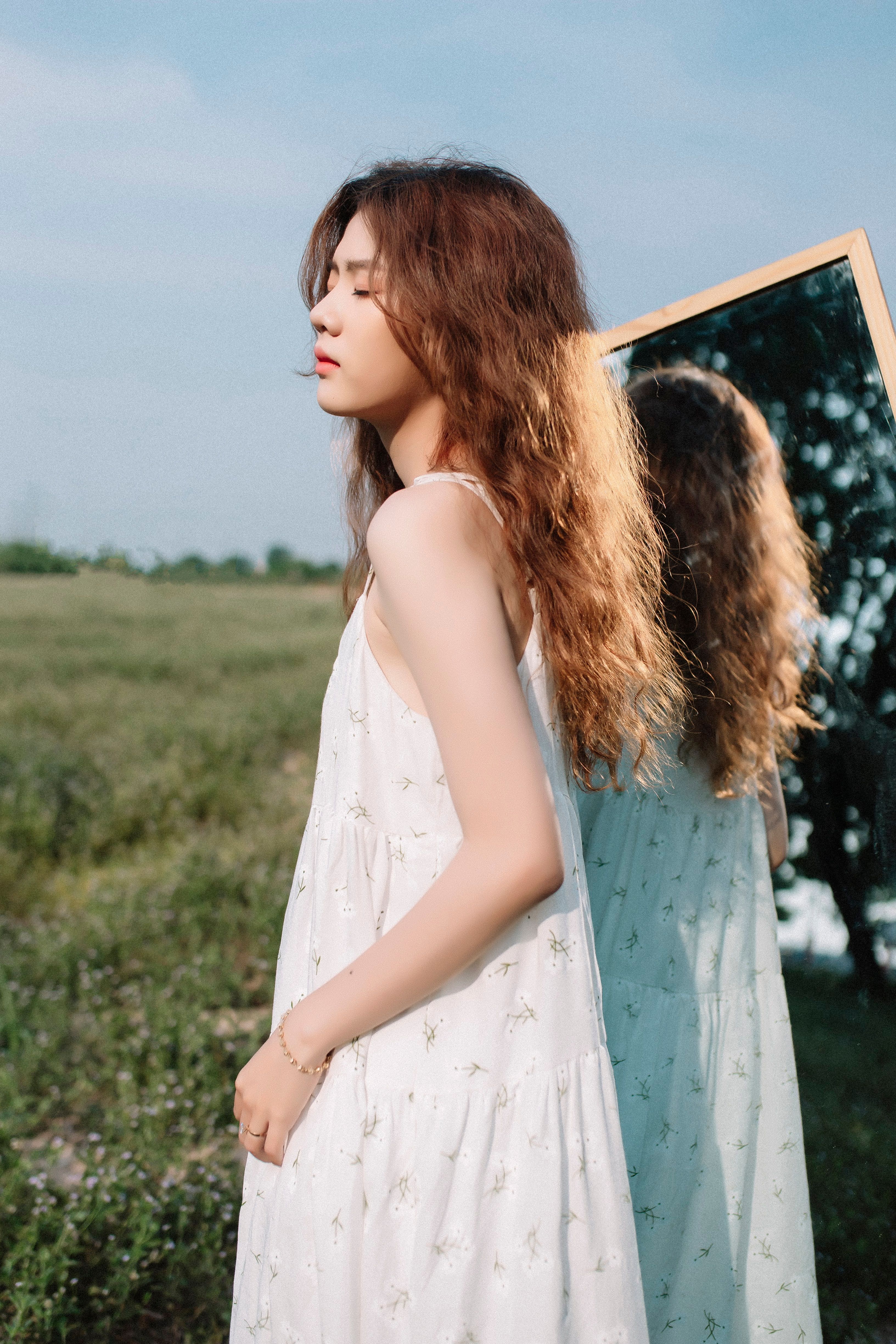A woman in a white dress standing in front of a mirror · Free Stock Photo
