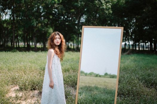 A Girl Standing in a Park with a Mirror 
