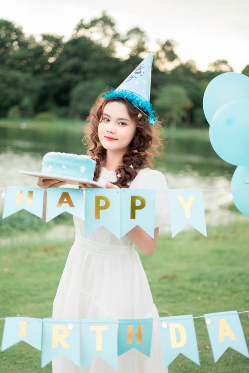 Free A young woman enjoying her birthday party by a lake with cake and decorations. Stock Photo