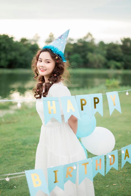 Free Smiling young woman enjoying a birthday celebration outdoors with festive decorations. Stock Photo