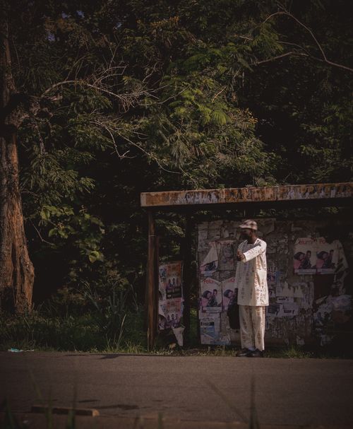 Free A man standing at a bus stop surrounded by lush trees in Ife, Nigeria, capturing a serene outdoor moment. Stock Photo