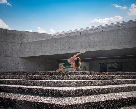 Woman performing yoga pose on stone steps in Ciudad de México, blending fitness and urban architecture.