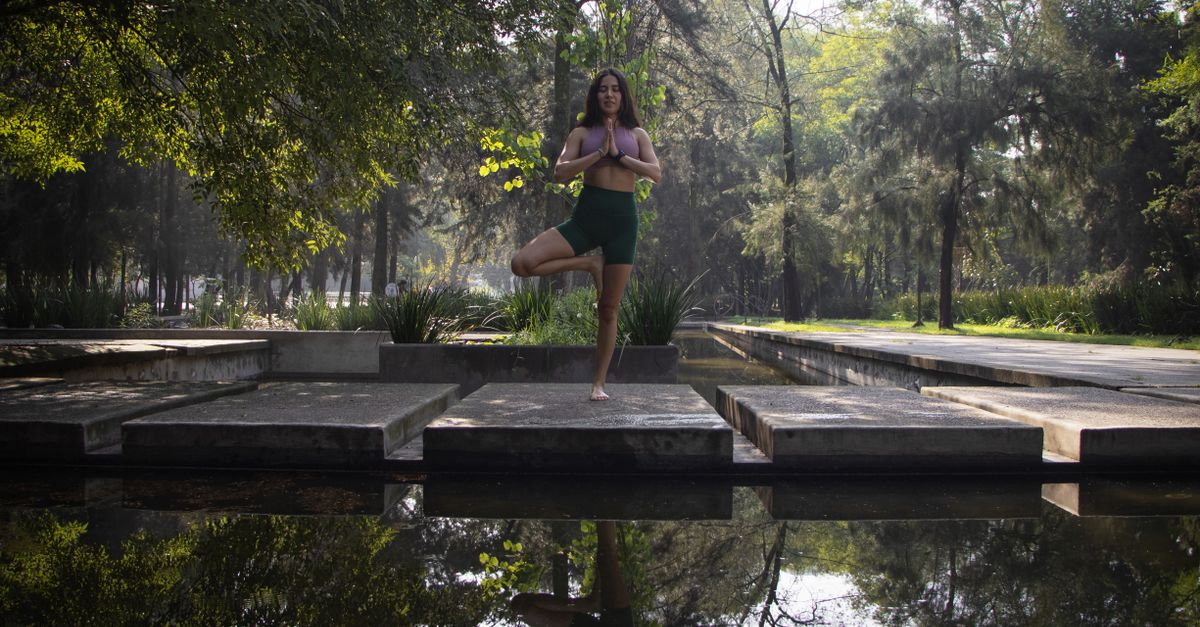 A person meditating in a busy city park, surrounded by skyscrapers, looking calm and centered