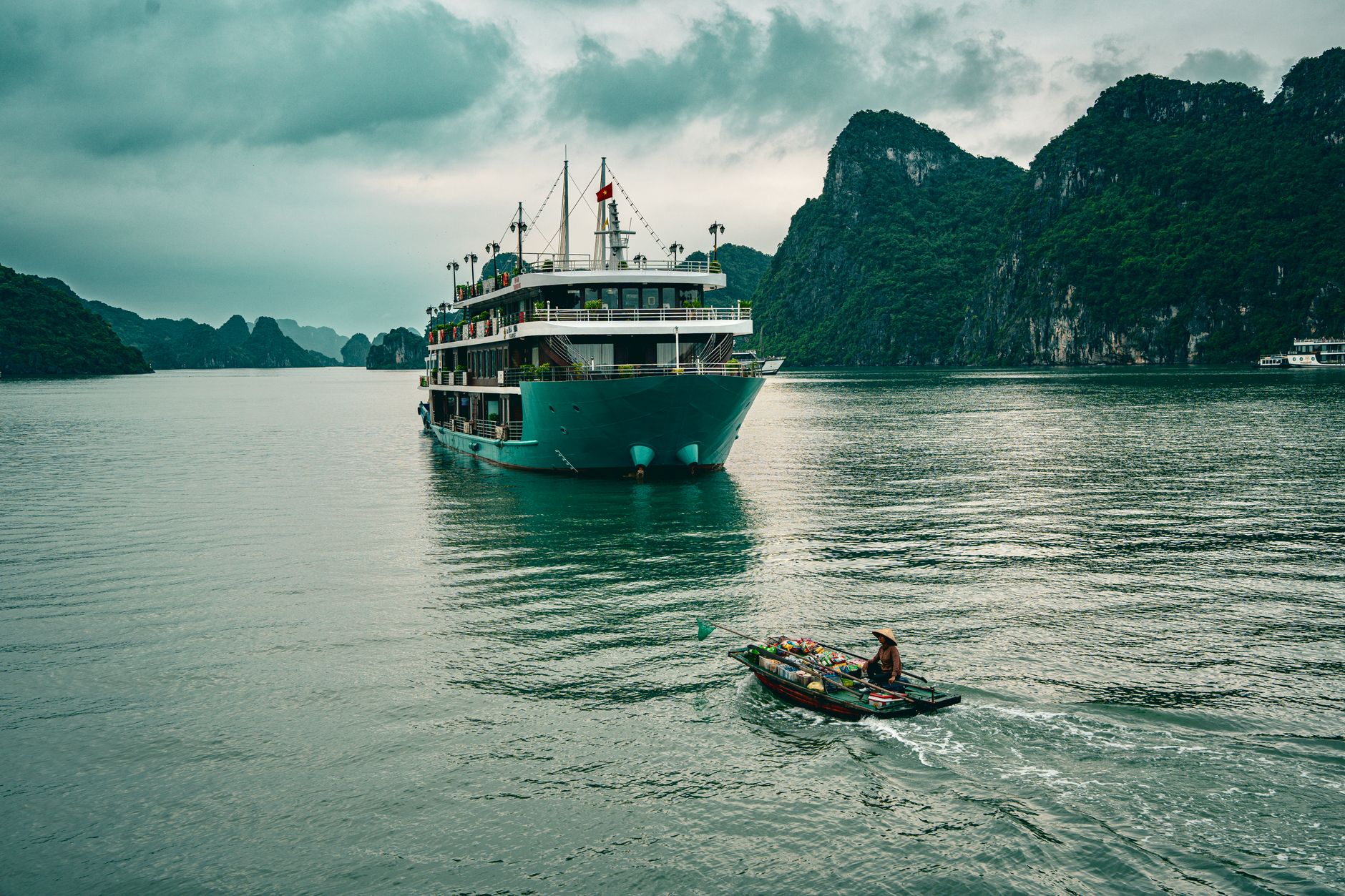 Majestic cruise boat sailing through the emerald waters of Halong Bay, Vietnam, surrounded by limestone formations.