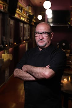 Portrait of a professional chef in a dimly lit restaurant interior, showcasing culinary expertise.