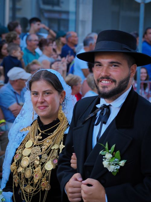 Free Couple in traditional wedding attire smiling at a cultural parade outdoors. Stock Photo