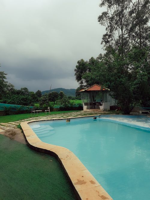 Free Relax by a tranquil pool amidst lush greenery in this tropical resort scene. Stock Photo