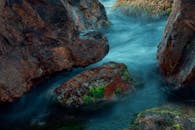 小溪平缓地流过青苔覆盖的岩石，营造出宁静的自然景观