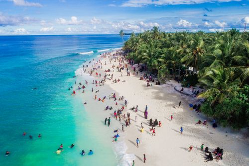 Free Aerial view of a tropical beach filled with people enjoying sun and sea. Stock Photo