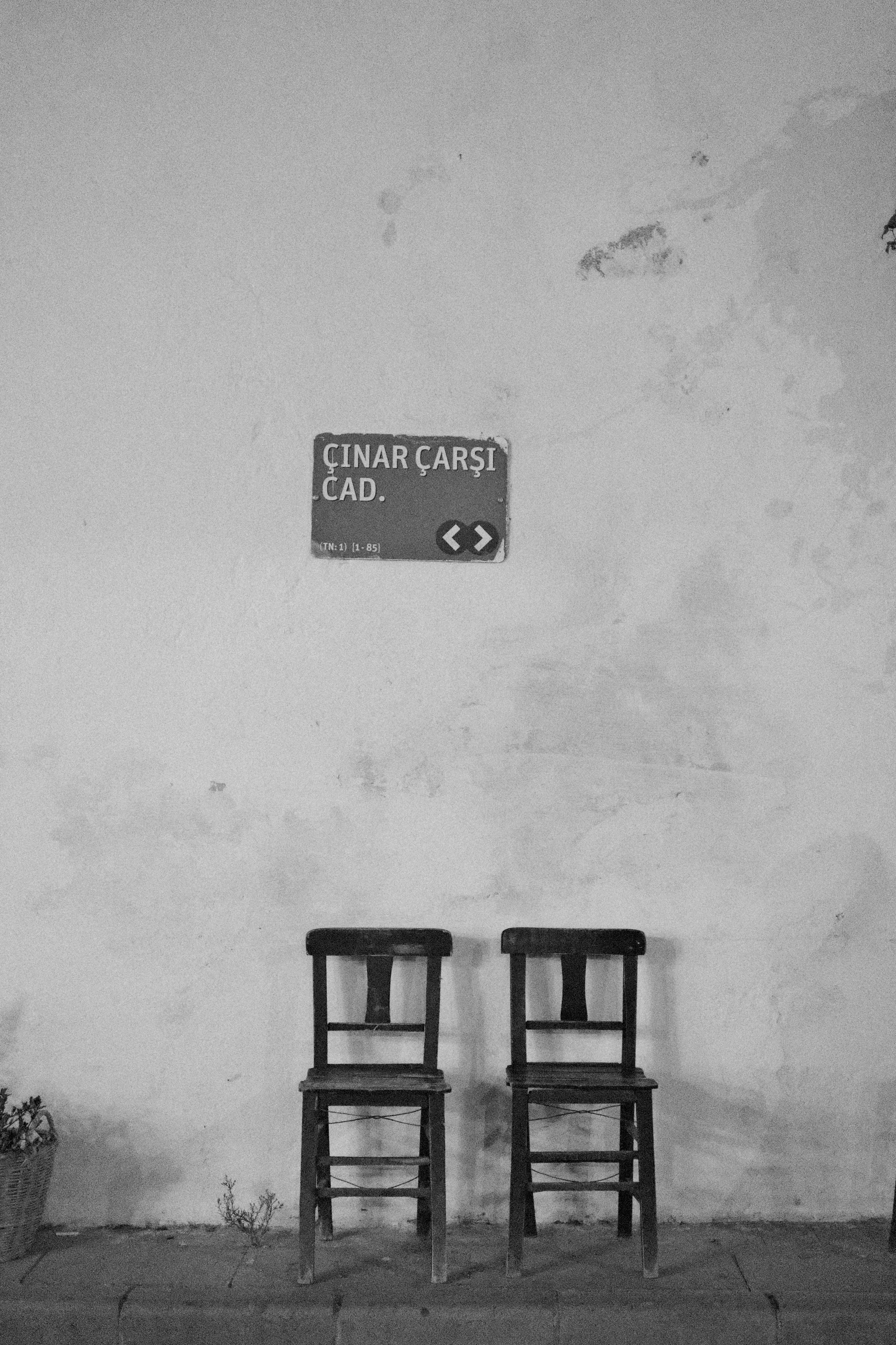 Two vintage chairs under a worn sign on a deserted street. Black and white photo.